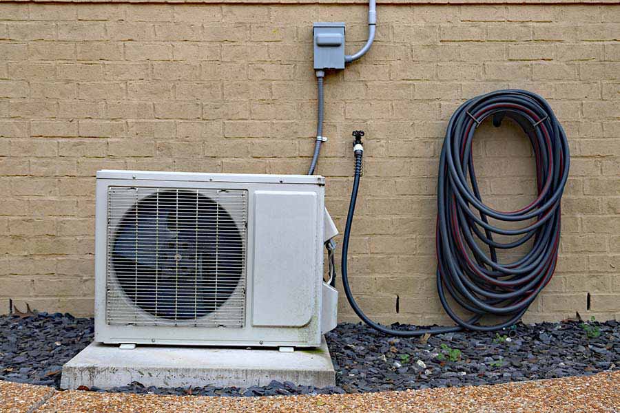 Outdoor AC condenser unit beside wall on
